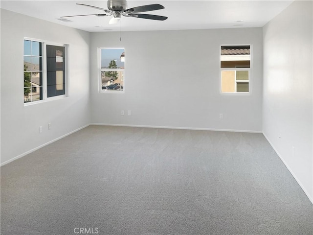 spare room with carpet flooring, ceiling fan, visible vents, and baseboards