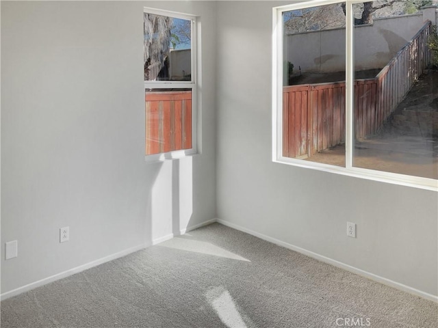 carpeted spare room featuring plenty of natural light and baseboards