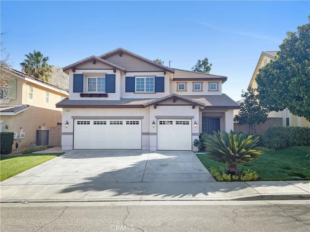 view of front of house featuring a tile roof, driveway, an attached garage, and stucco siding