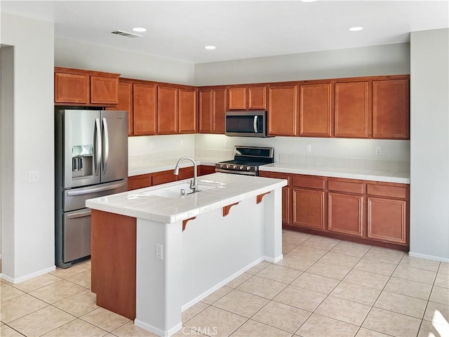 kitchen featuring tile countertops, stainless steel appliances, visible vents, light tile patterned flooring, and a sink