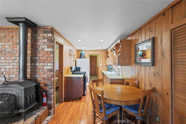 dining area with recessed lighting, light wood-style flooring, a wood stove, and wood walls