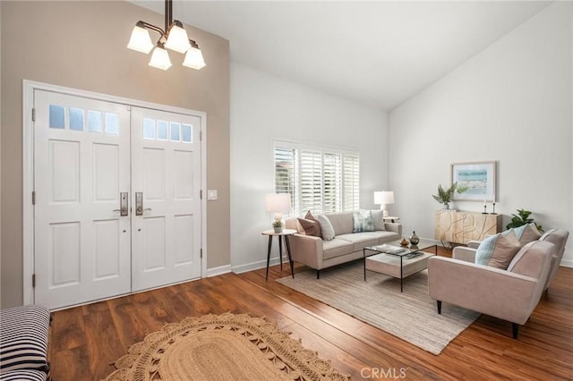 living room featuring a notable chandelier, high vaulted ceiling, wood finished floors, and baseboards