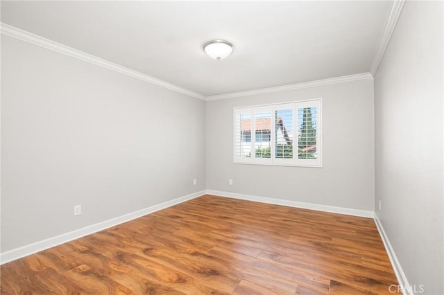 empty room with crown molding, baseboards, and wood finished floors