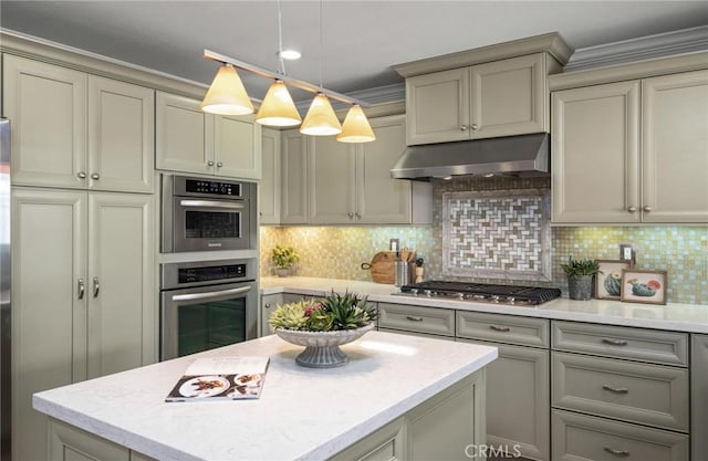 kitchen with decorative light fixtures, stainless steel gas cooktop, light countertops, backsplash, and under cabinet range hood