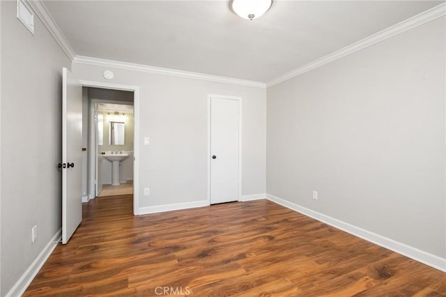 unfurnished bedroom with ornamental molding, dark wood-style flooring, and baseboards