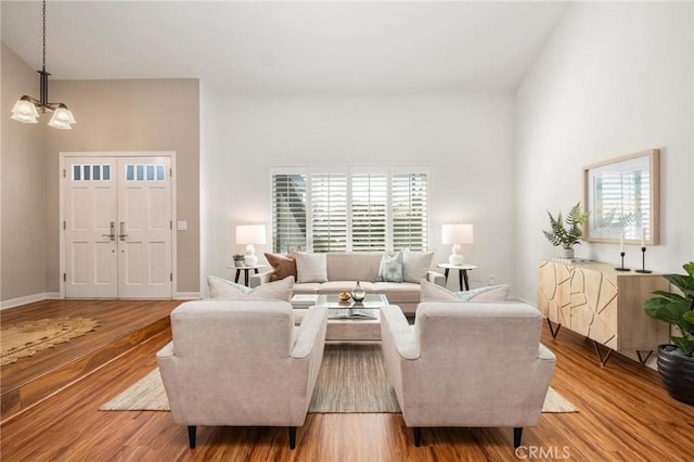 living room with light wood-style floors, a chandelier, and baseboards