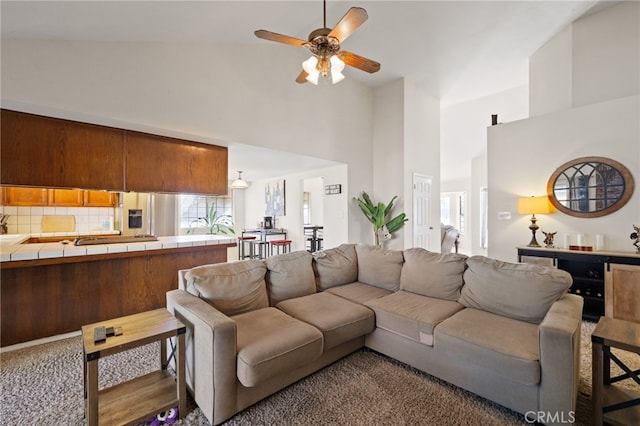 living room featuring carpet floors, ceiling fan, and a towering ceiling