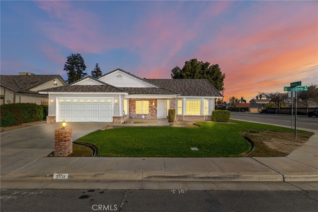 view of front of home featuring concrete driveway, brick siding, a lawn, and an attached garage