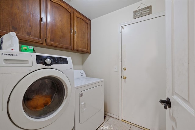 washroom with cabinet space, light tile patterned floors, and washer and dryer