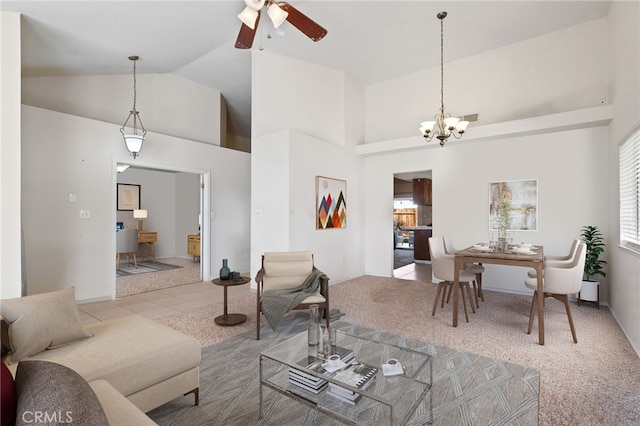 carpeted living room with high vaulted ceiling, ceiling fan with notable chandelier, plenty of natural light, and tile patterned floors