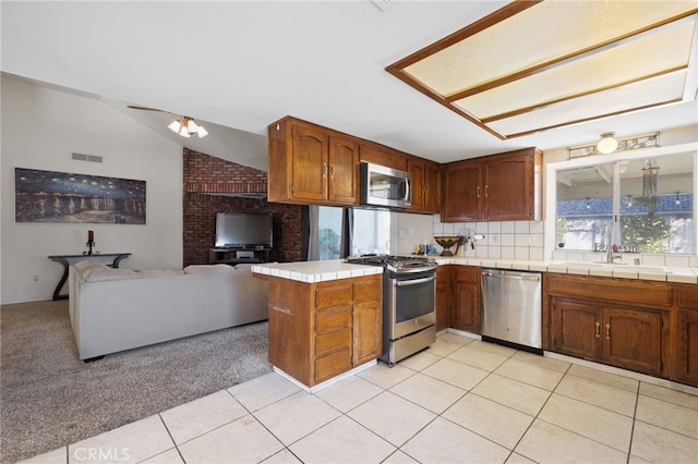 kitchen featuring plenty of natural light, appliances with stainless steel finishes, open floor plan, a peninsula, and a sink