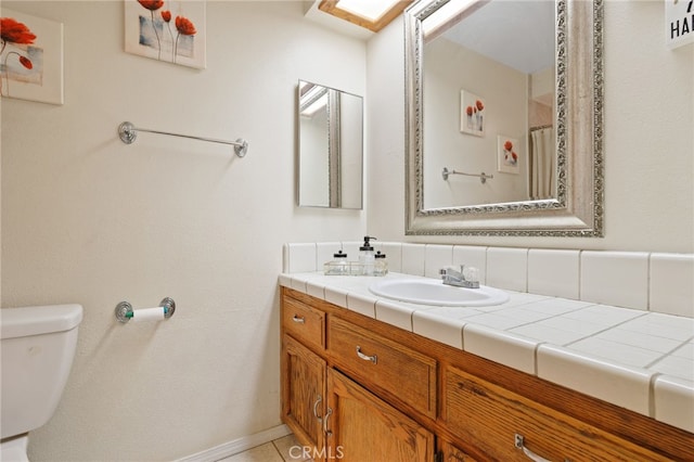 bathroom featuring toilet, vanity, and baseboards