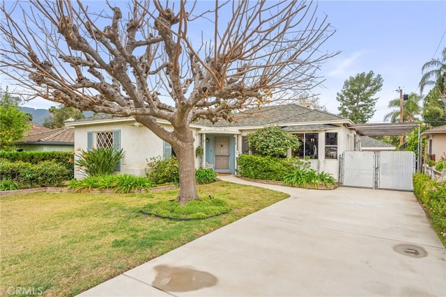 view of front of house with driveway, a front lawn, a gate, and stucco siding