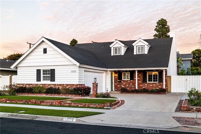 cape cod-style house with concrete driveway, brick siding, fence, and an attached garage