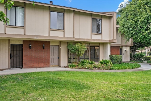 townhome / multi-family property with a front yard and brick siding