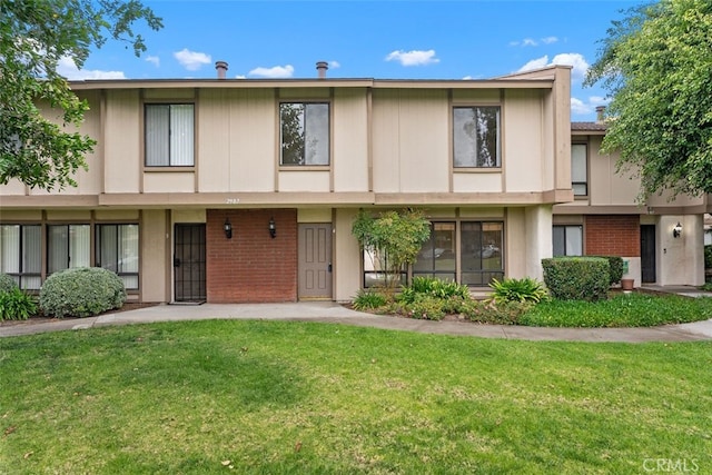 multi unit property with brick siding and a front yard