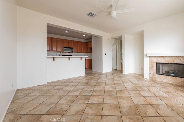 unfurnished living room featuring light tile patterned flooring, recessed lighting, visible vents, a high end fireplace, and a ceiling fan