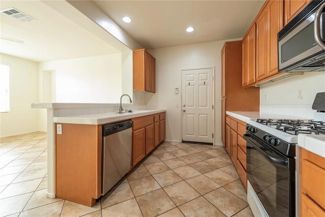 kitchen with a sink, visible vents, light countertops, appliances with stainless steel finishes, and brown cabinets