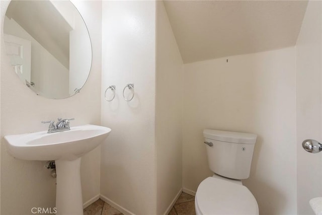 bathroom with toilet, tile patterned flooring, baseboards, and a sink