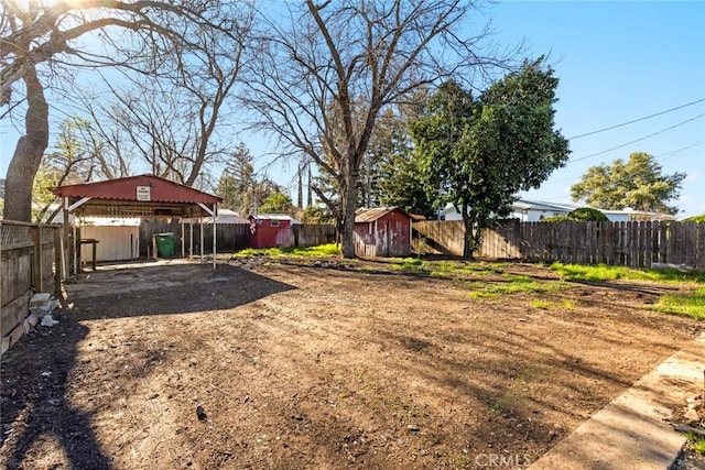 view of yard featuring a carport, an outbuilding, a fenced backyard, and a storage shed