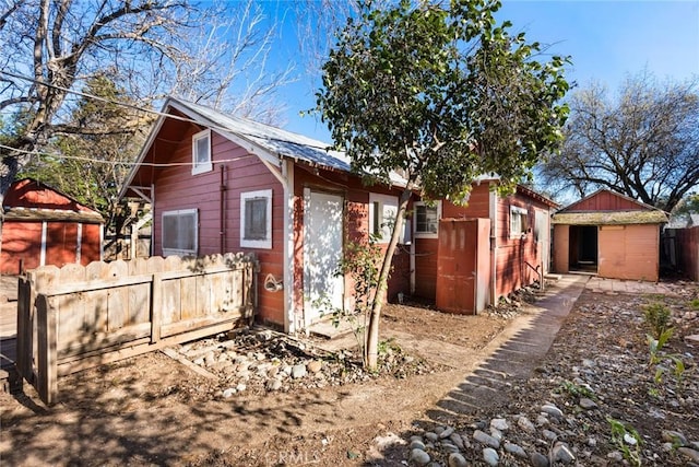 exterior space featuring a shed, fence, and an outbuilding