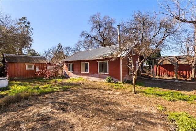 rear view of property featuring metal roof, an outdoor structure, and a storage unit