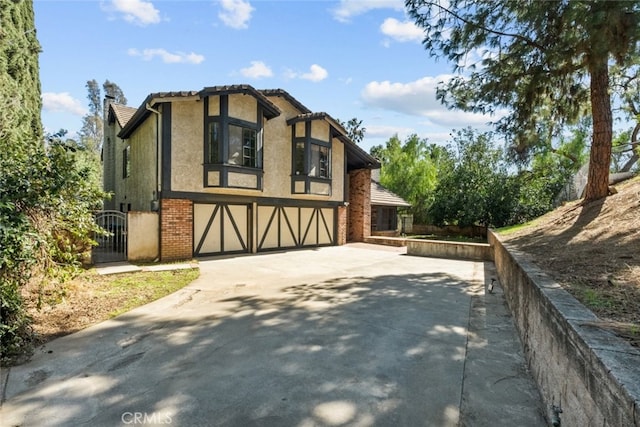 exterior space featuring concrete driveway, brick siding, an attached garage, and stucco siding