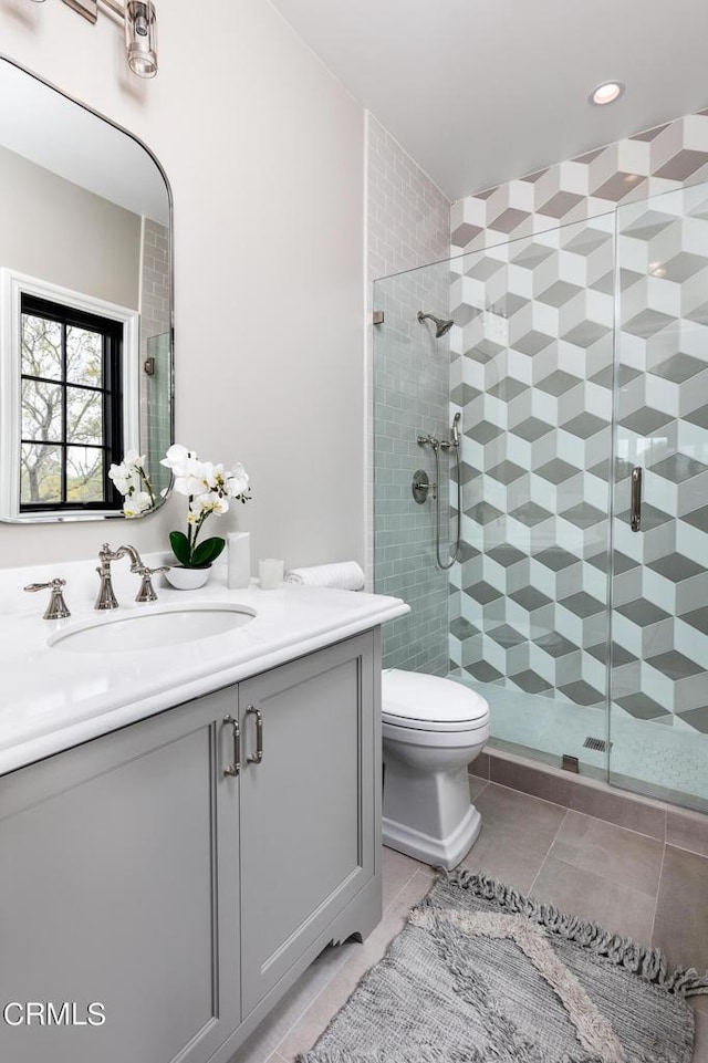 full bath with toilet, a stall shower, vanity, and tile patterned floors