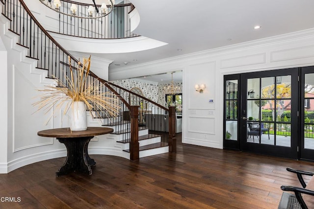 foyer featuring a chandelier, ornamental molding, stairs, and a decorative wall