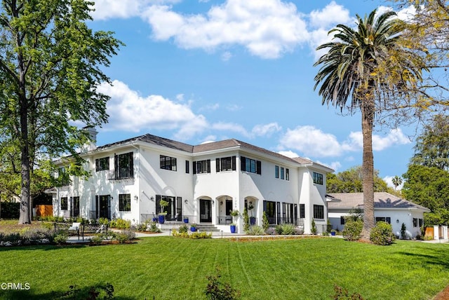 rear view of property featuring a yard, a chimney, and stucco siding