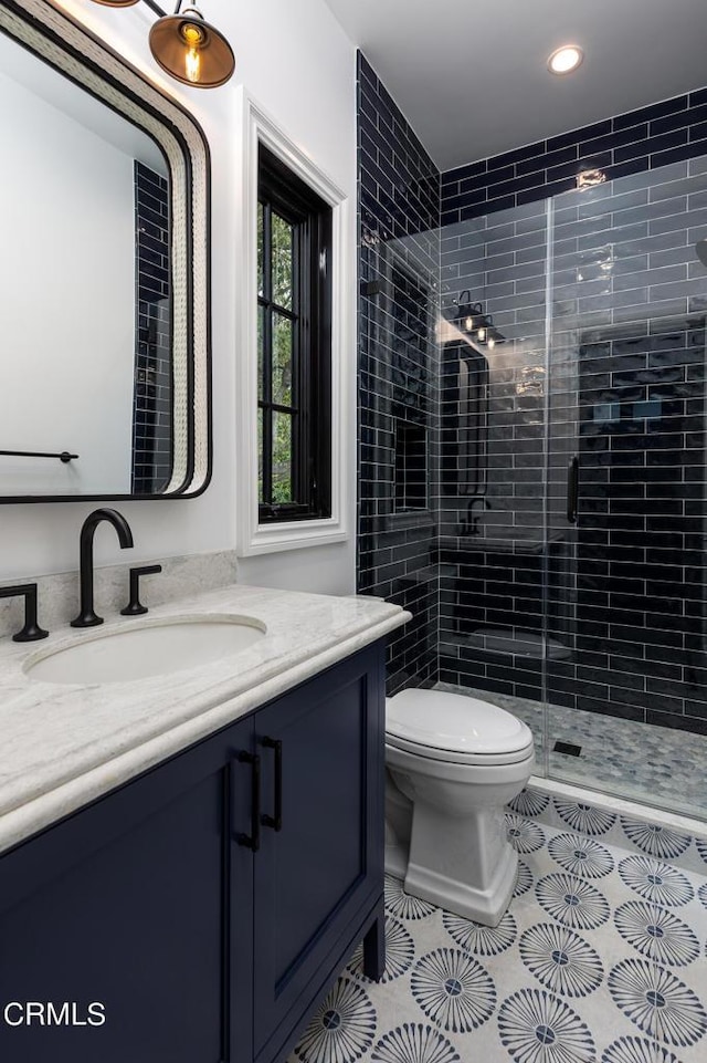 bathroom featuring tile patterned flooring, toilet, recessed lighting, vanity, and a shower stall