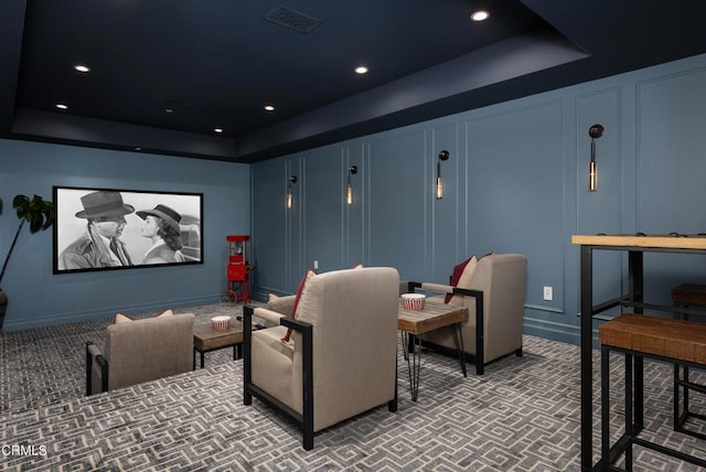 home theater featuring a tray ceiling, a decorative wall, visible vents, and recessed lighting