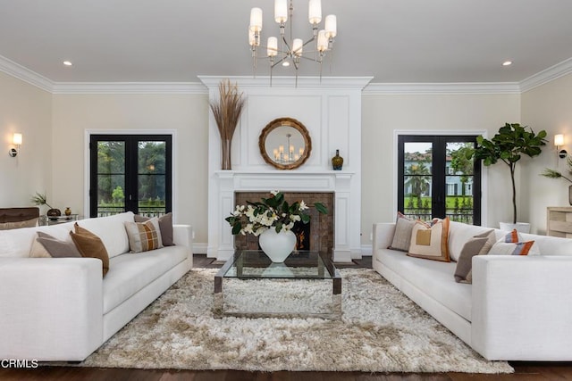 living area featuring ornamental molding, french doors, a fireplace, and a notable chandelier