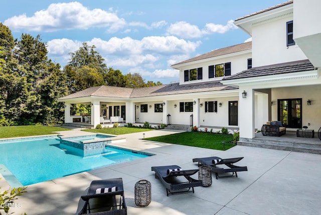 rear view of house with a patio, a yard, a pool with connected hot tub, and an outdoor living space