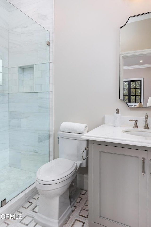 bathroom featuring toilet, ornamental molding, a shower stall, vanity, and tile patterned floors