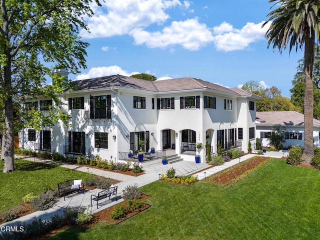 rear view of house with a patio area, a yard, and stucco siding