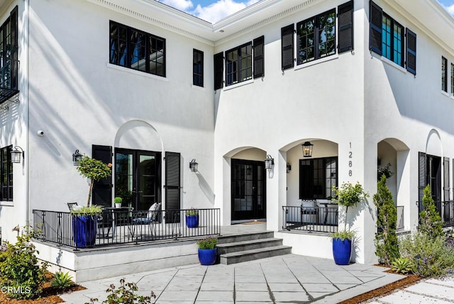 rear view of property featuring covered porch and stucco siding