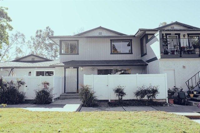 view of front of house featuring a fenced front yard, a front yard, and a balcony