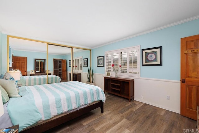 bedroom with baseboards, a closet, wood finished floors, and crown molding