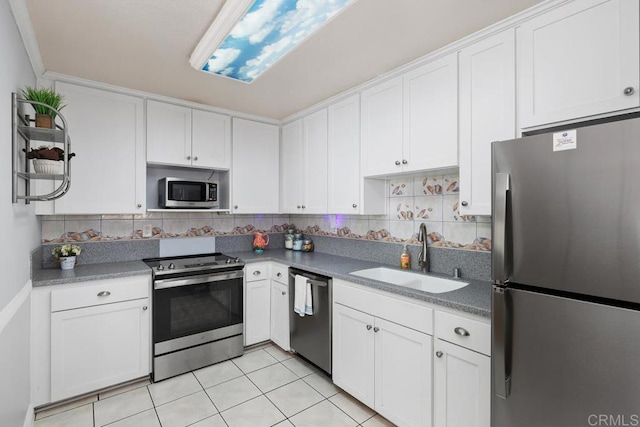 kitchen with stainless steel appliances, dark countertops, white cabinets, and a sink