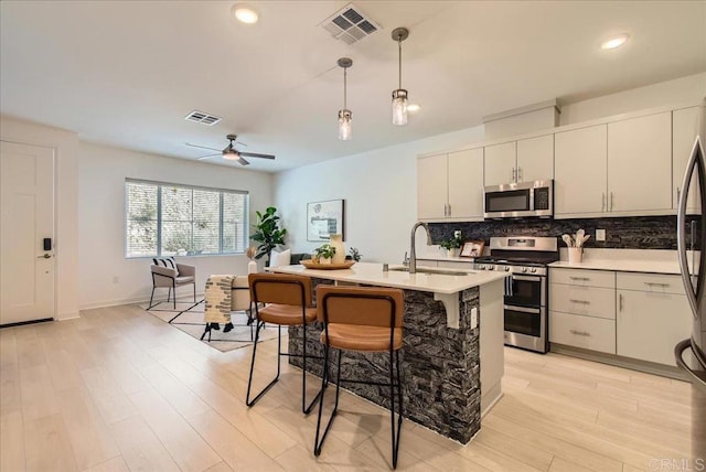 35107 Rangpur Ln, Fallbrook, CA 92028 - kitchen with stainless steel appliances, a sink, decorative backsplash, light countertops, and light wood-style flooring