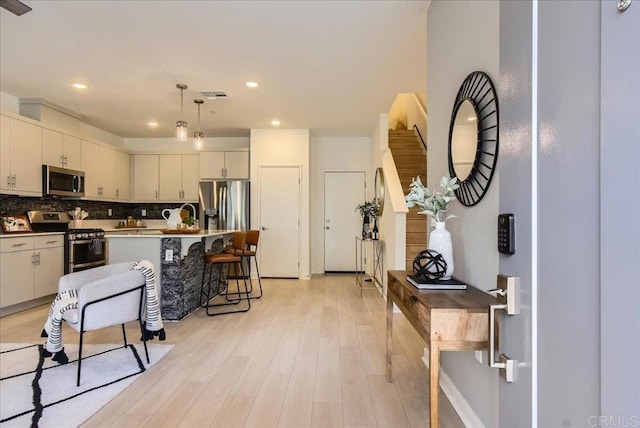 35107 Rangpur Ln, Fallbrook, CA 92028 - kitchen featuring stainless steel appliances, light wood-type flooring, decorative backsplash, pendant lighting, and a kitchen breakfast bar