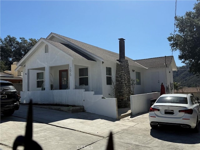 view of front facade with a shingled roof, fence, and stucco siding