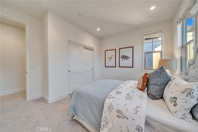 bedroom featuring baseboards, a closet, recessed lighting, and light colored carpet