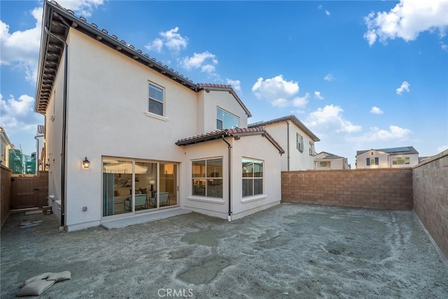 rear view of house featuring a fenced backyard, a patio, a tiled roof, and stucco siding