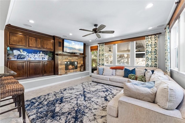 tiled living area featuring ornamental molding, a stone fireplace, a ceiling fan, and recessed lighting