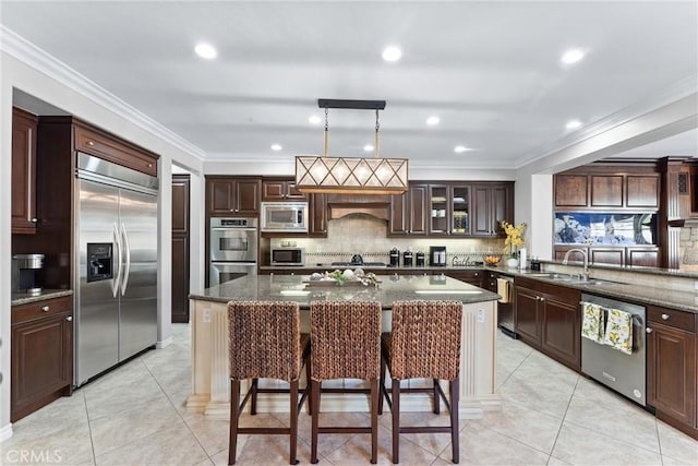 kitchen featuring light tile patterned floors, a center island, built in appliances, a kitchen bar, and a sink