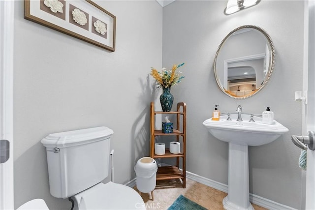 half bathroom with toilet, tile patterned flooring, and baseboards