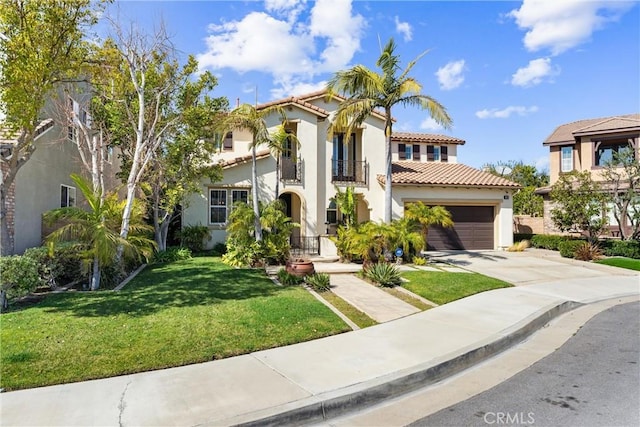 mediterranean / spanish house featuring stucco siding, an attached garage, a balcony, driveway, and a front lawn