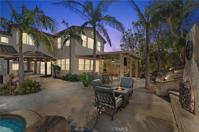 view of patio featuring a fire pit, an outdoor kitchen, a ceiling fan, and a gazebo